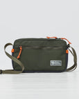 Green crossbody bag with orange accents on a light gray background