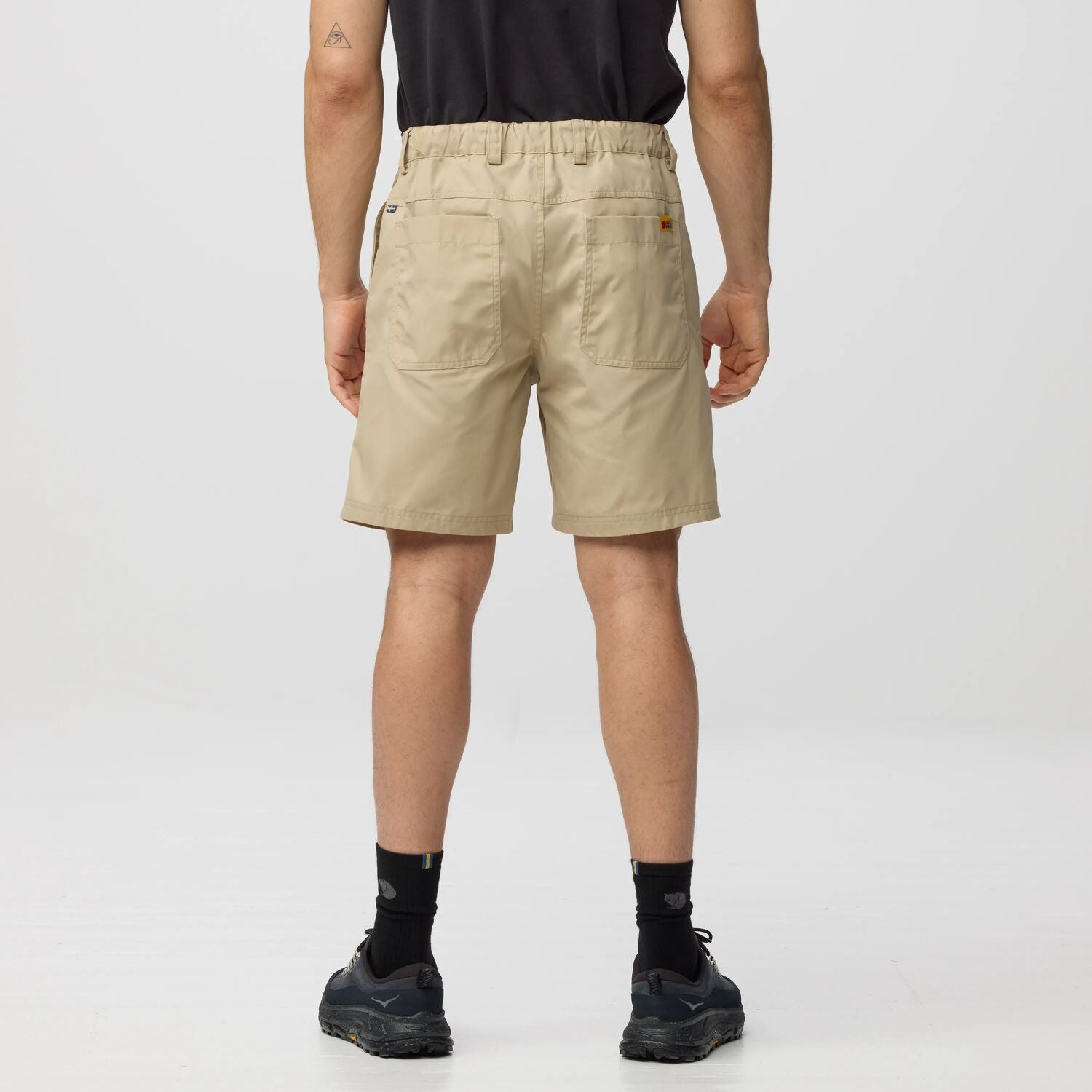 Person wearing beige shorts on a plain background