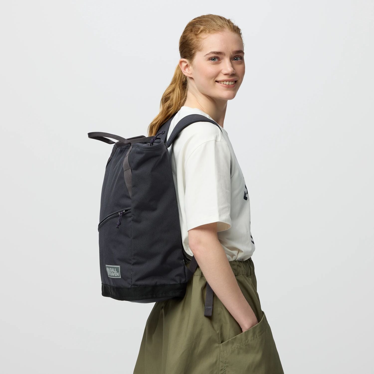 Person wearing a black backpack on a plain background