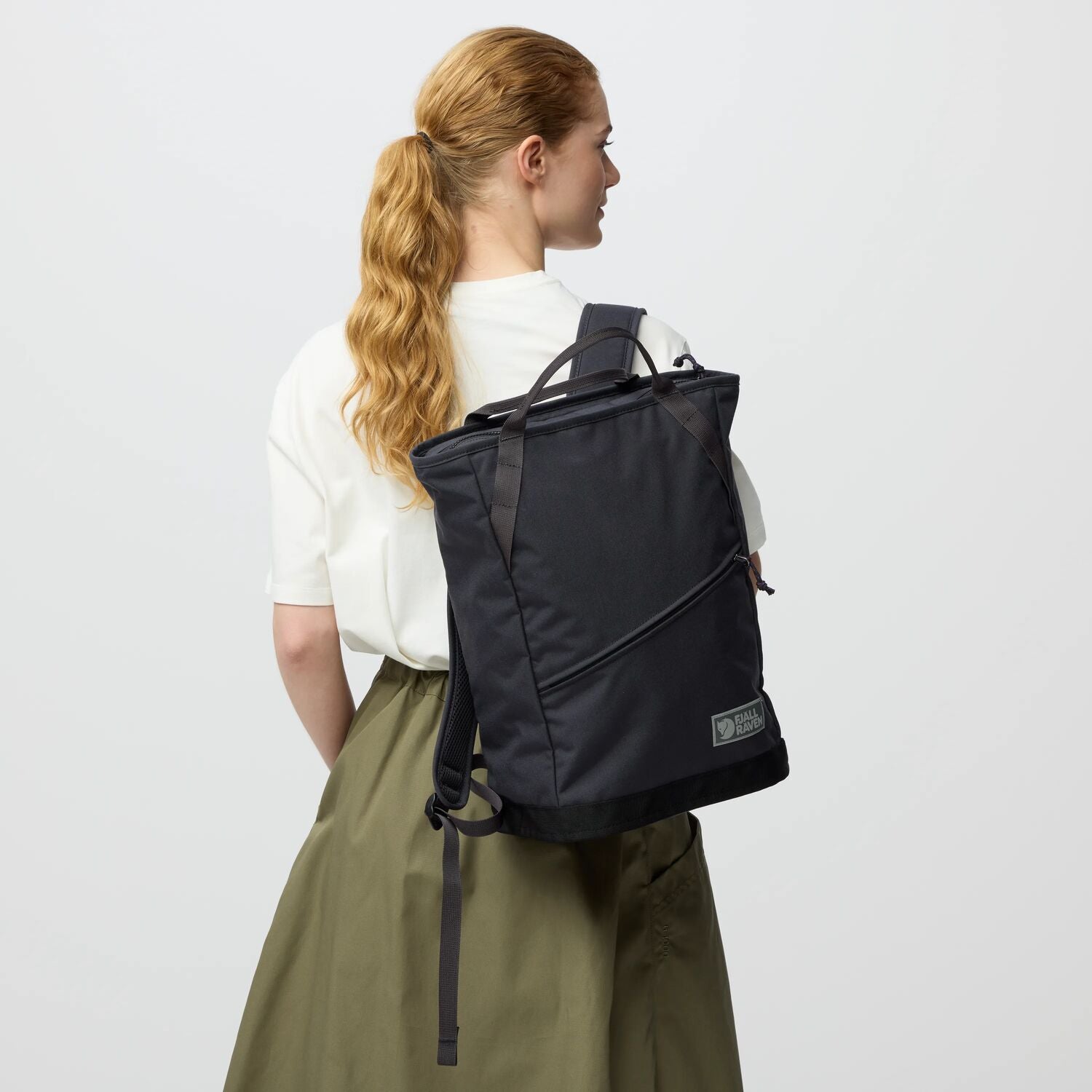 Person wearing a black backpack on a plain background