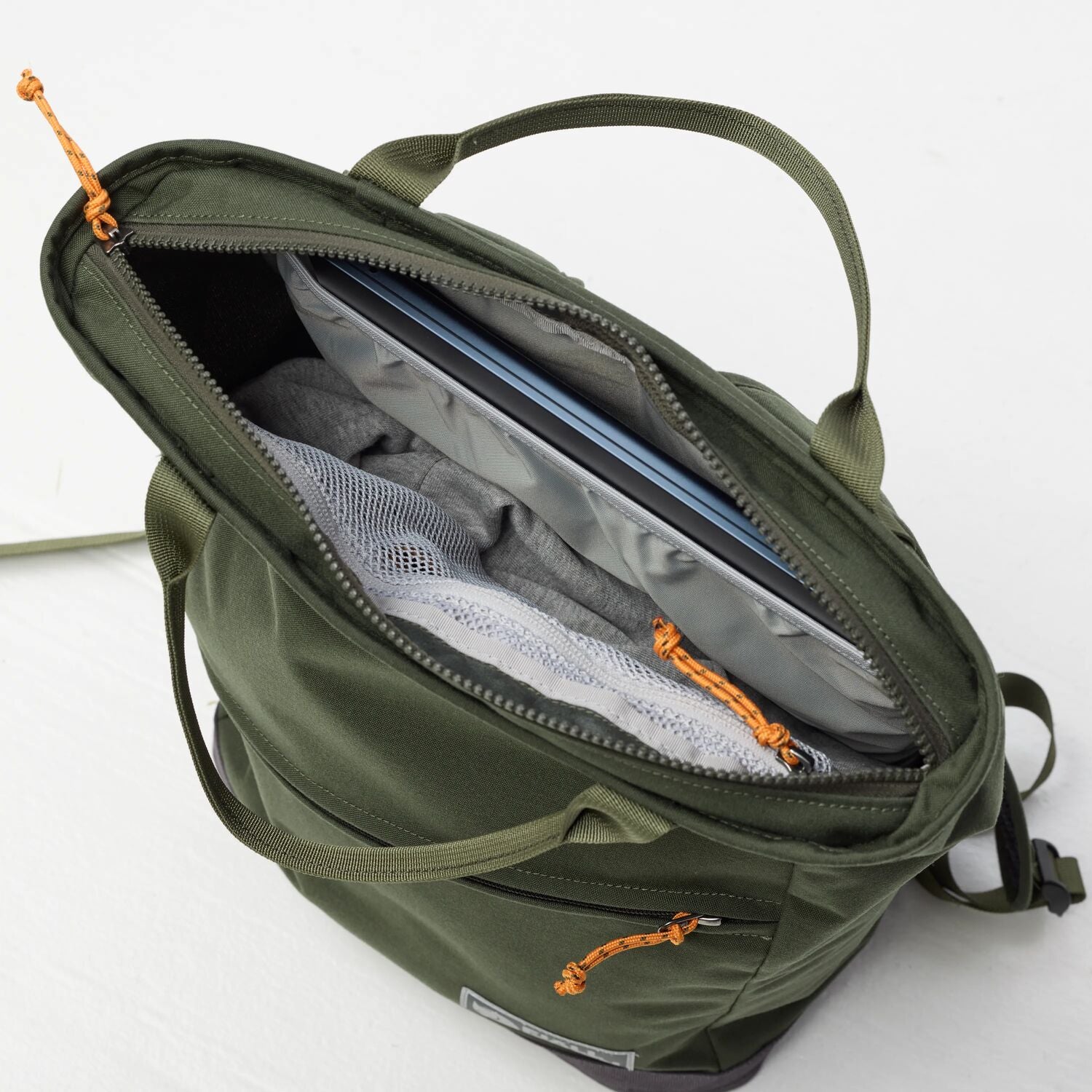 Green backpack with open compartment showing organized contents on a white background