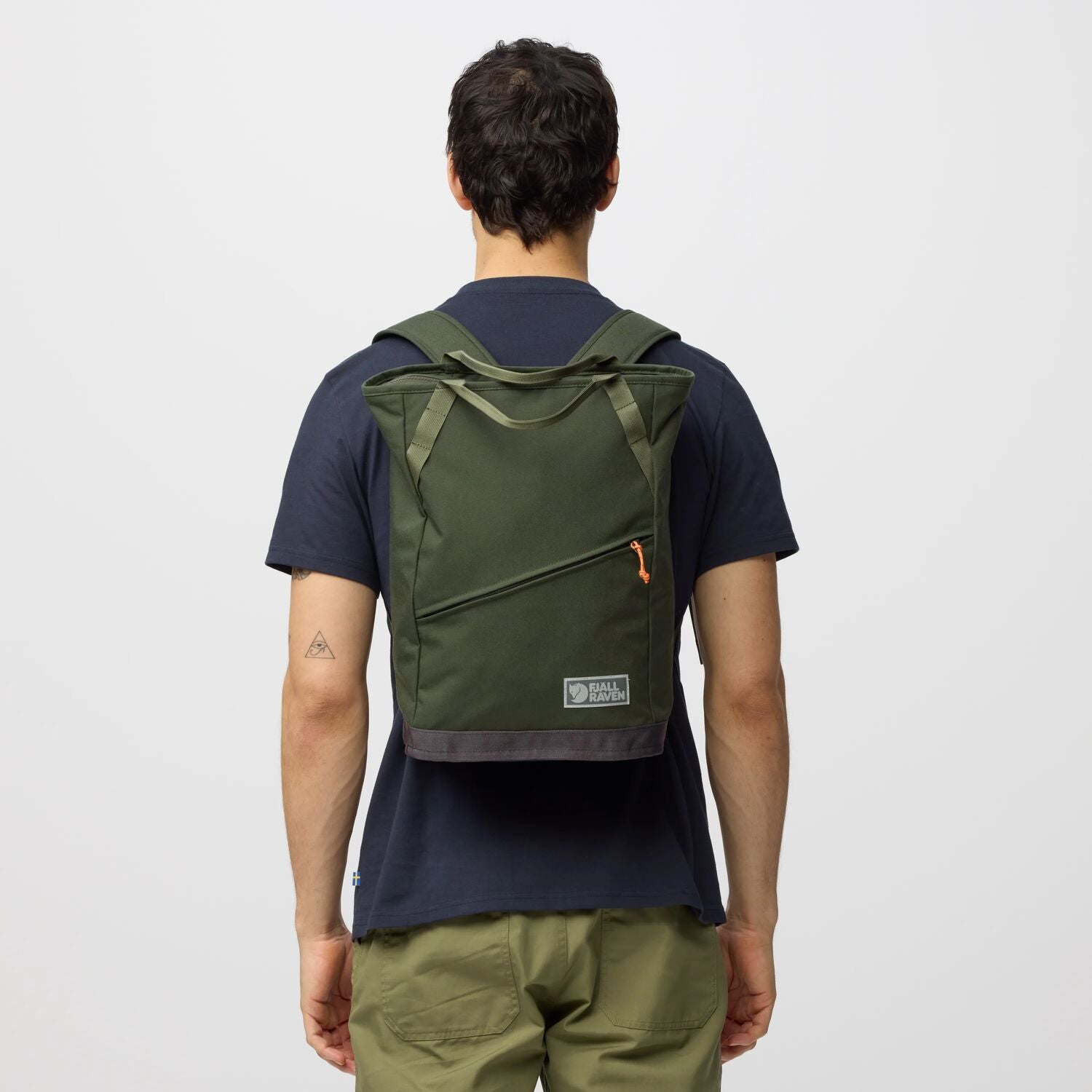 Person wearing a green backpack on a plain background