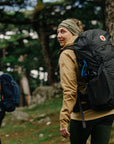 Person with a large black backpack hiking in a forest