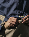 Person buttoning up on a jacket with a blurred natural background