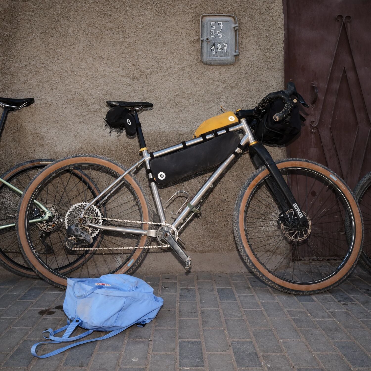 Bicycle with gear packs and a blue bag on a sidewalk