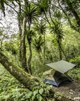 Tent set up in a dense forest with lush greenery