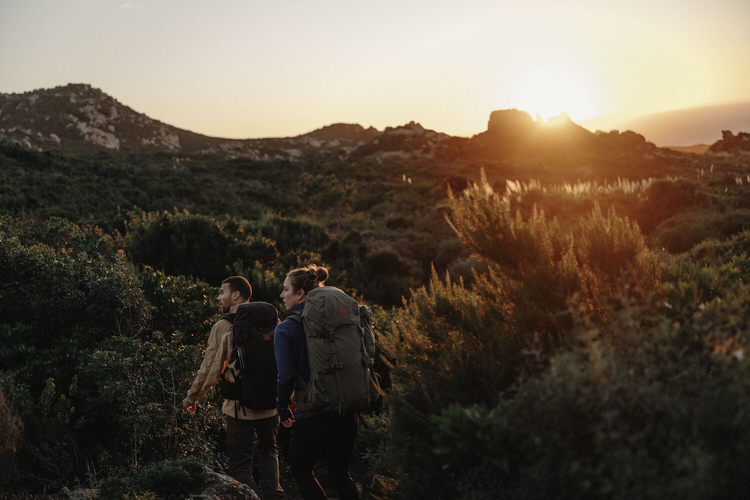 a couple carrying trekking backpacks and trekking in the highlands