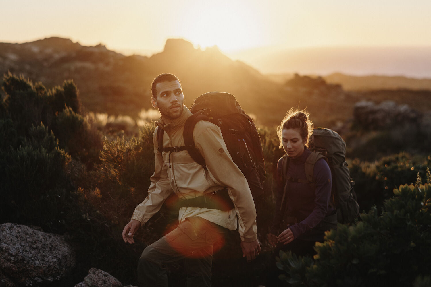 a couple carrying trekking backpacks and trekking in the mountains