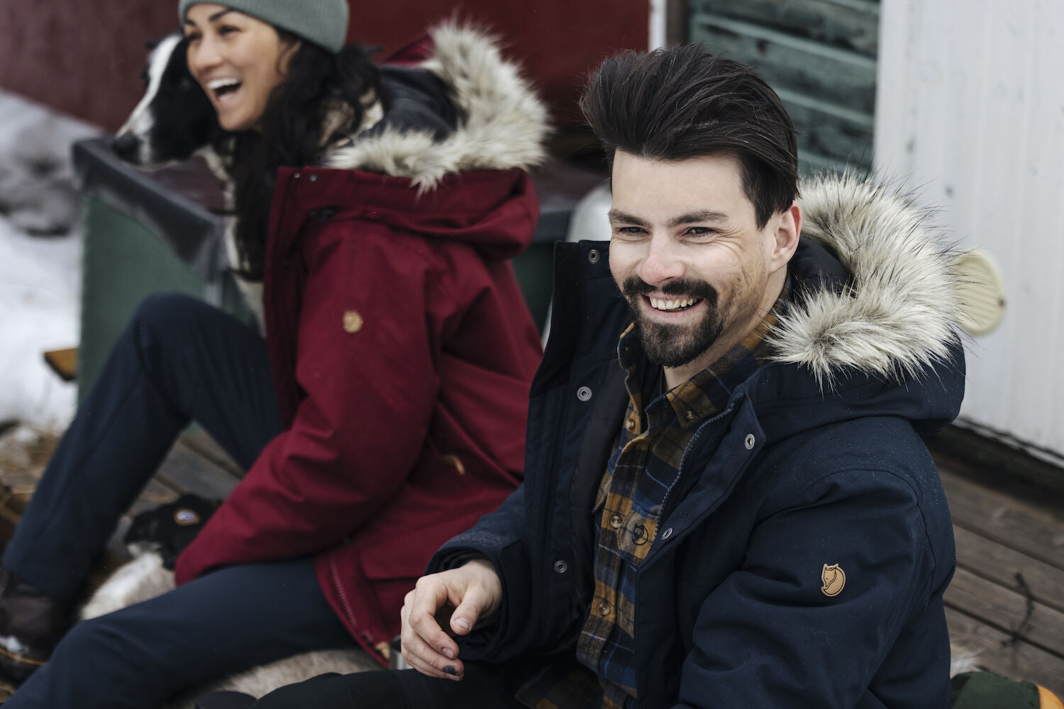 couple sitting on a bench wearing winter jackets with fur hood