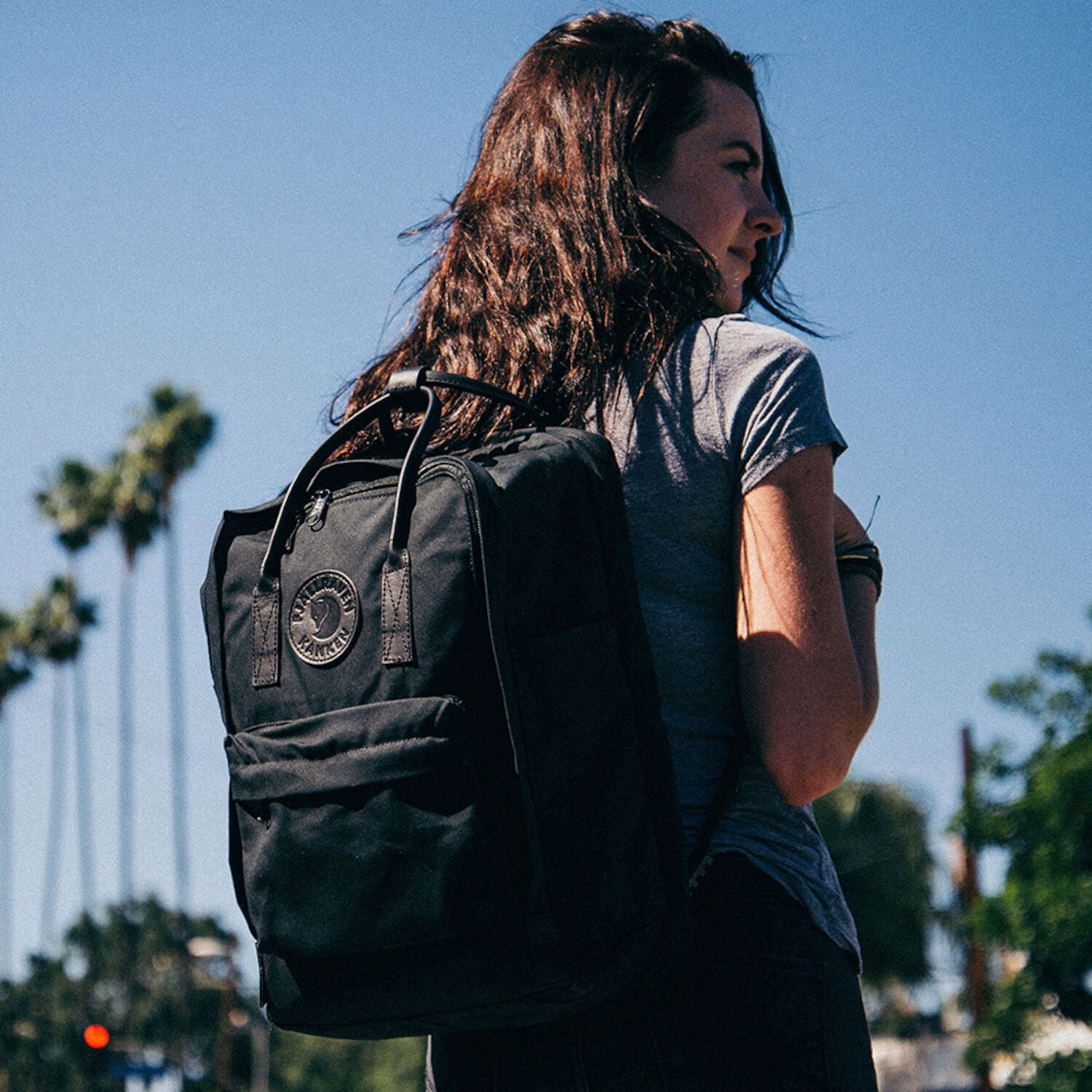 woman carrying kanken black backpack on the street