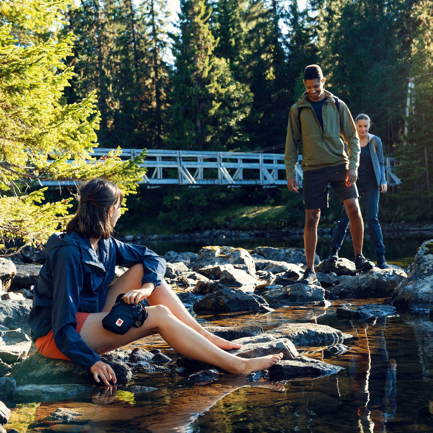 people hanging out on stones on a stream