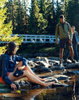 people hanging out on stones on a stream