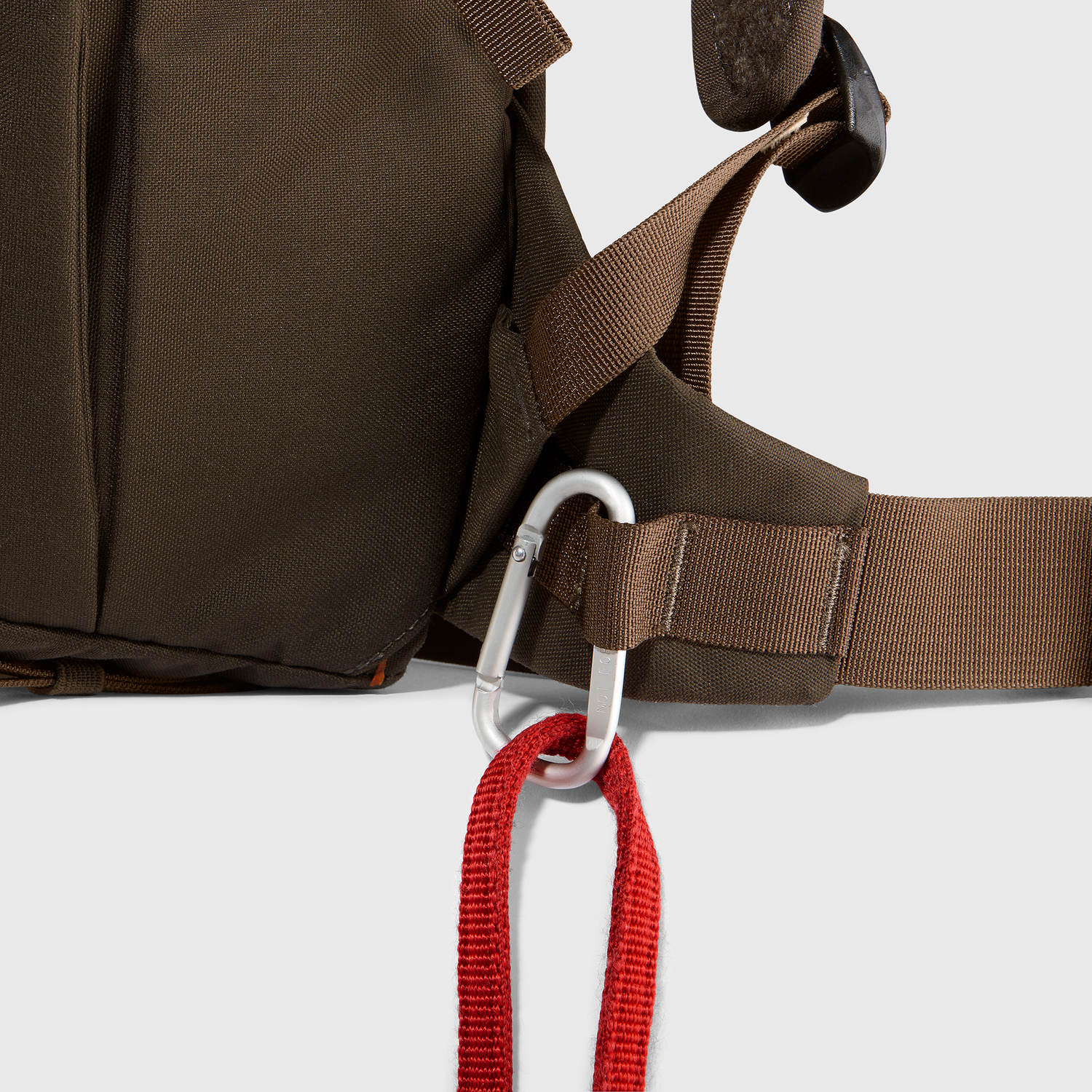 Brown backpack with a carabiner and red rope on a white background
