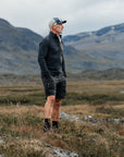 Man standing in a mountainous landscape wearing athletic gear.