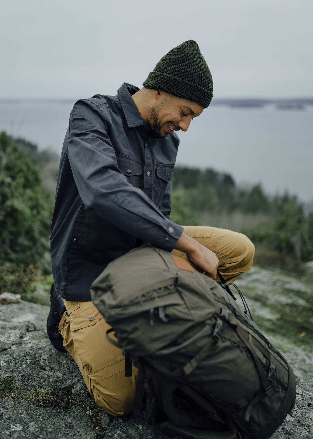 Man sitting on a rock with a backpack outdoors