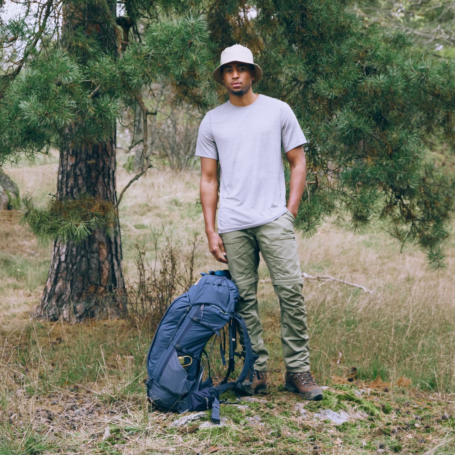 Man standing in a forest with a blue backpack