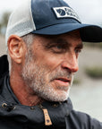 Man wearing a cap with a Fjällräven logo outdoors