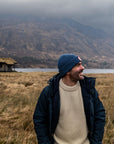 Man standing in a field with mountains and a lake in the background