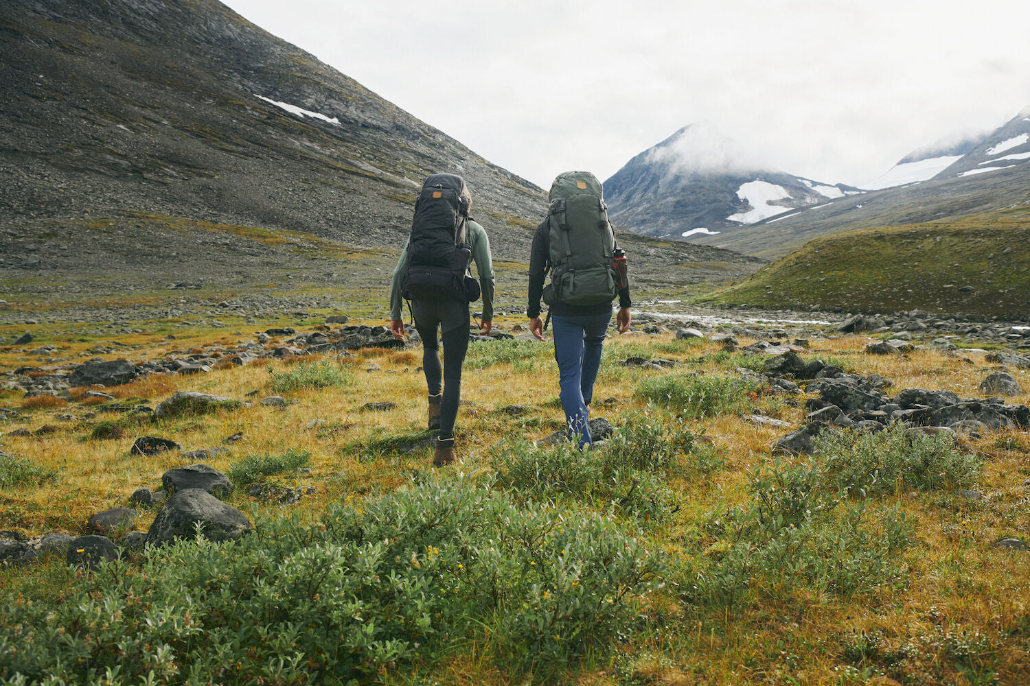 two men carrying trekking backpack and trekking along the mountain