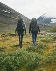 two men carrying trekking backpack and trekking along the mountain