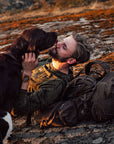man lying on his trekking backpack on mountain surface kissing his dog