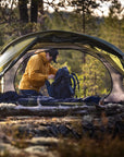 Person setting up a tent in a forested area