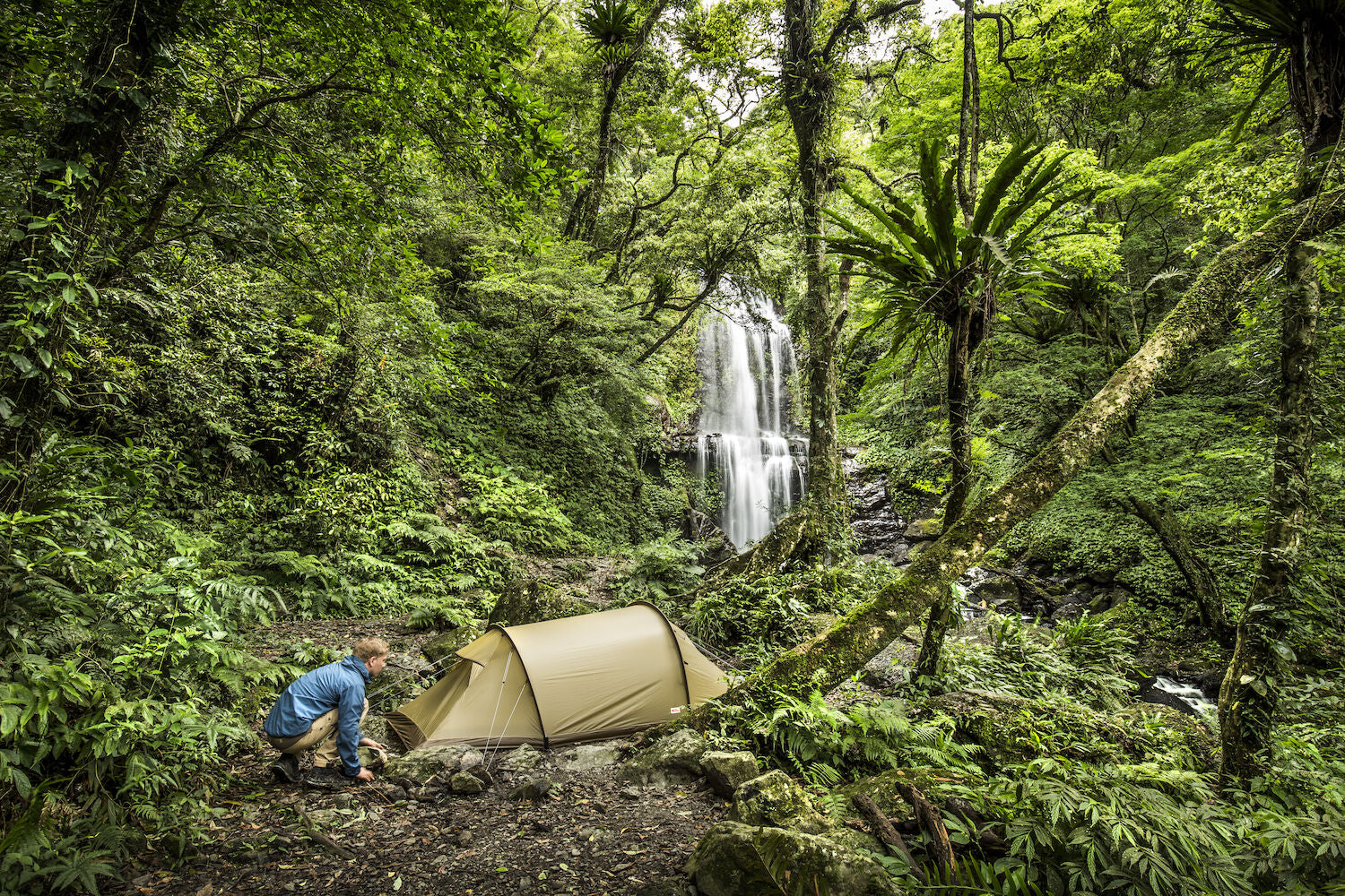 camping tent set up near the waterfall in a forest