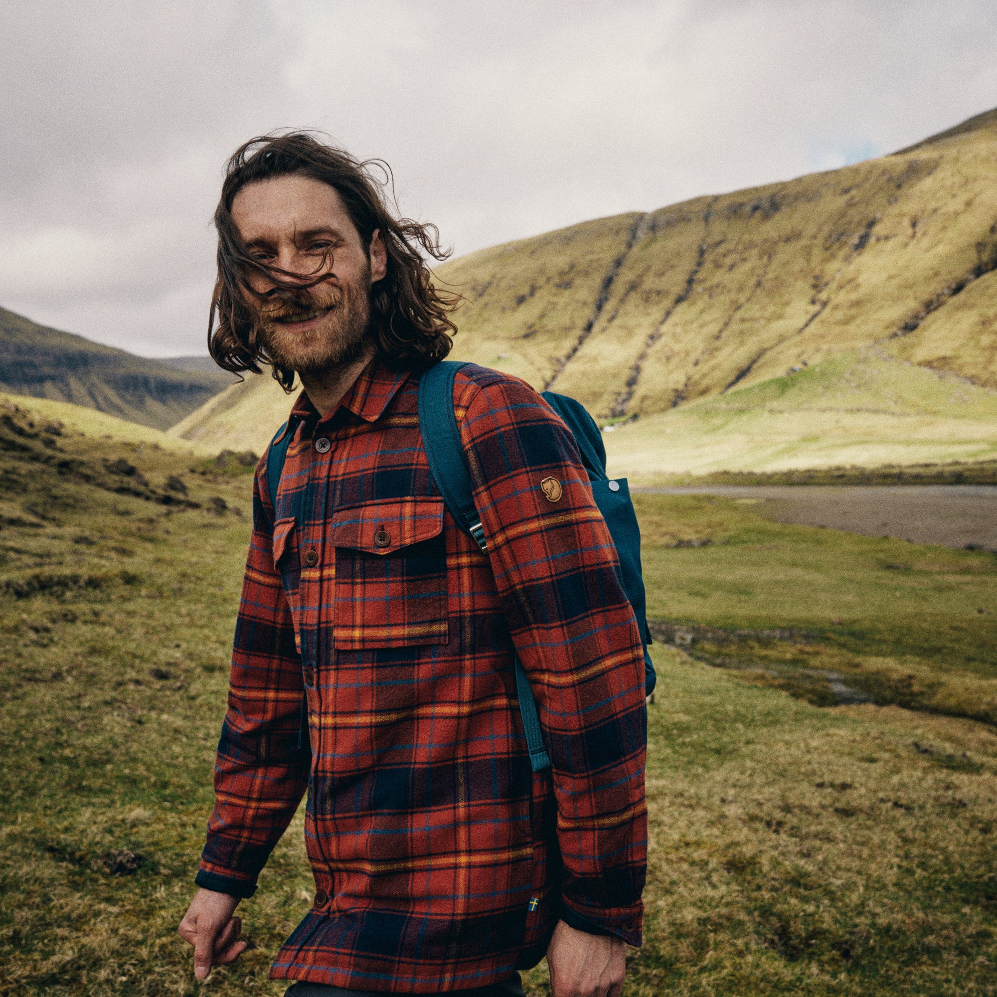 man wearing autumn leaf-dark navy long sleeve shirt walking along a grass terrain