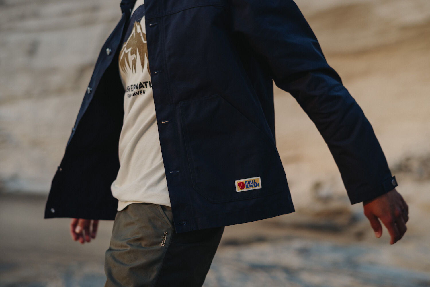 man wearing white shirt and navy outerwear with Fjällräven logo
