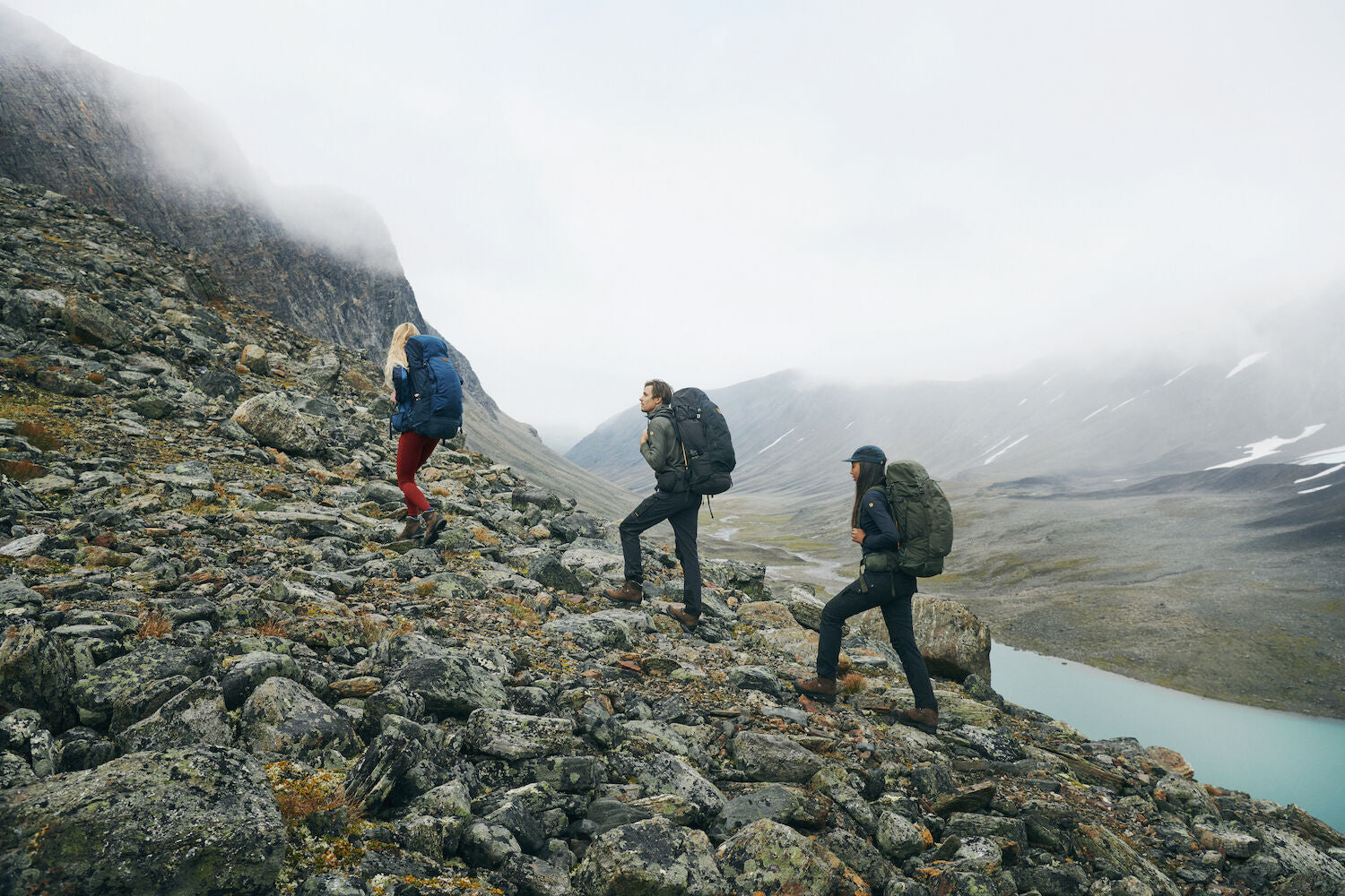 three men carrying trekking backpack trekking along rocky slopes