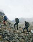 three men carrying trekking backpack trekking along rocky slopes