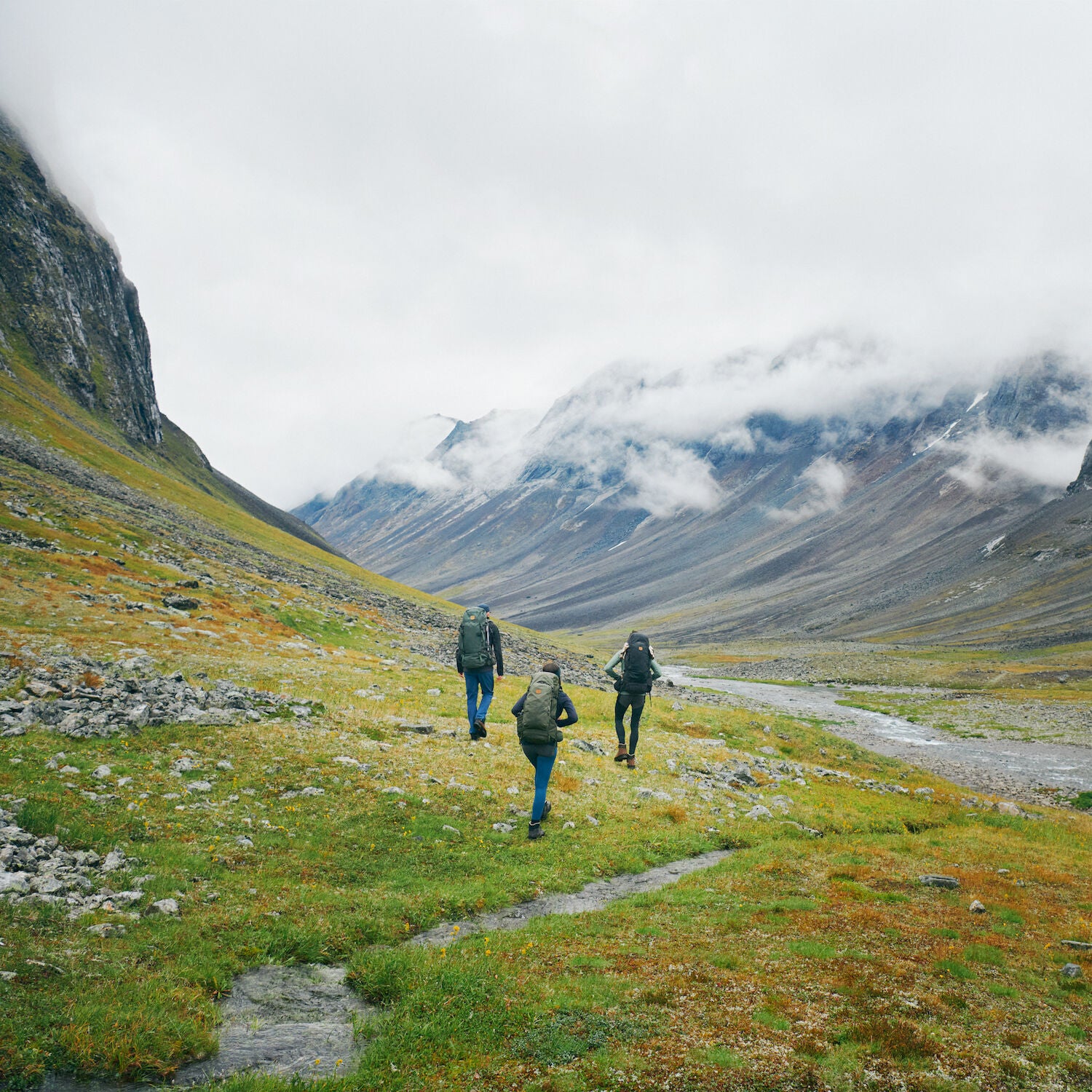 three men carrying trekking backpack trekking on a mountain