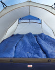 Blue sleeping bags inside a tent with a clear blue sky background