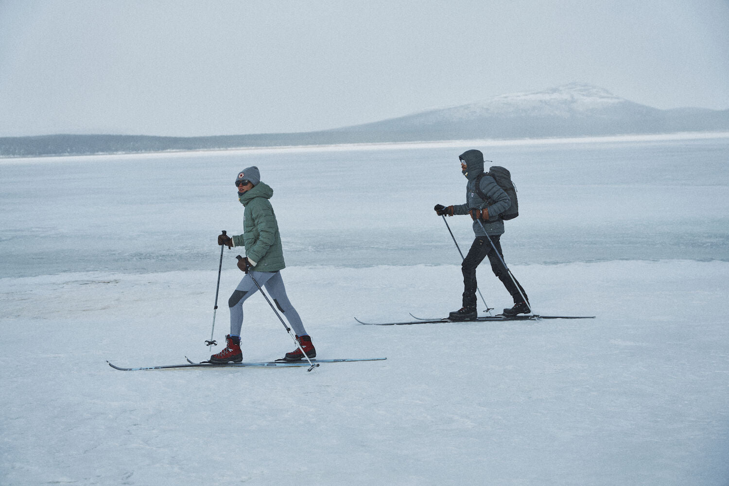 two men skiing wearing padded down winter jacket