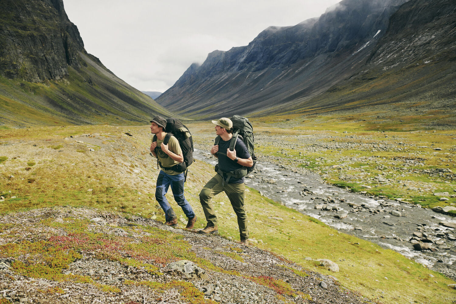 two men carrying trekking backpack trekking on a mountain
