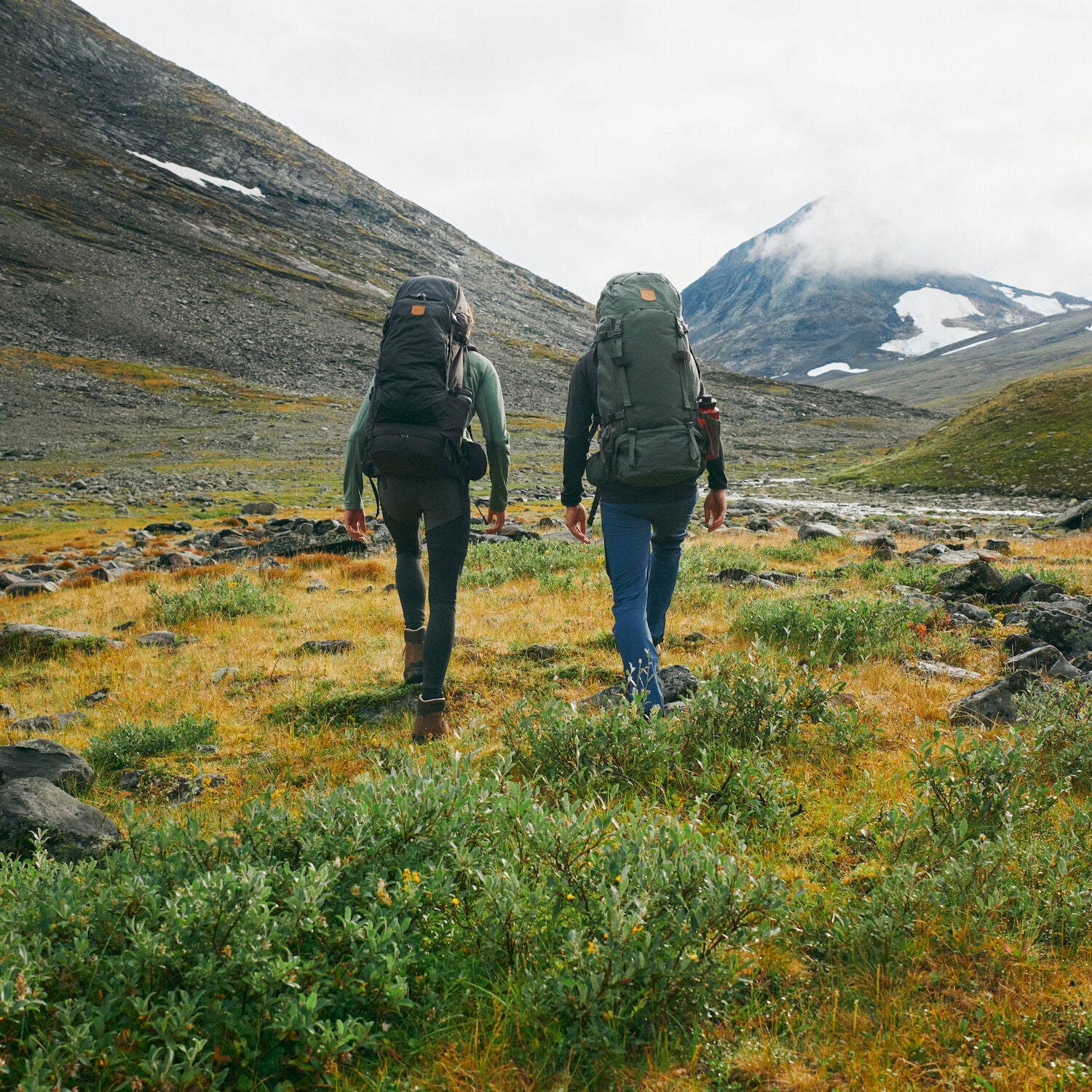 two men carrying trekking backpack trekking on a mountain
