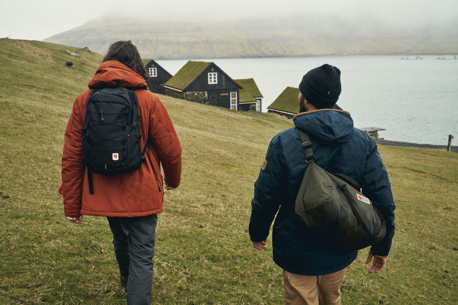 two men carrying bags hiking on a mountain