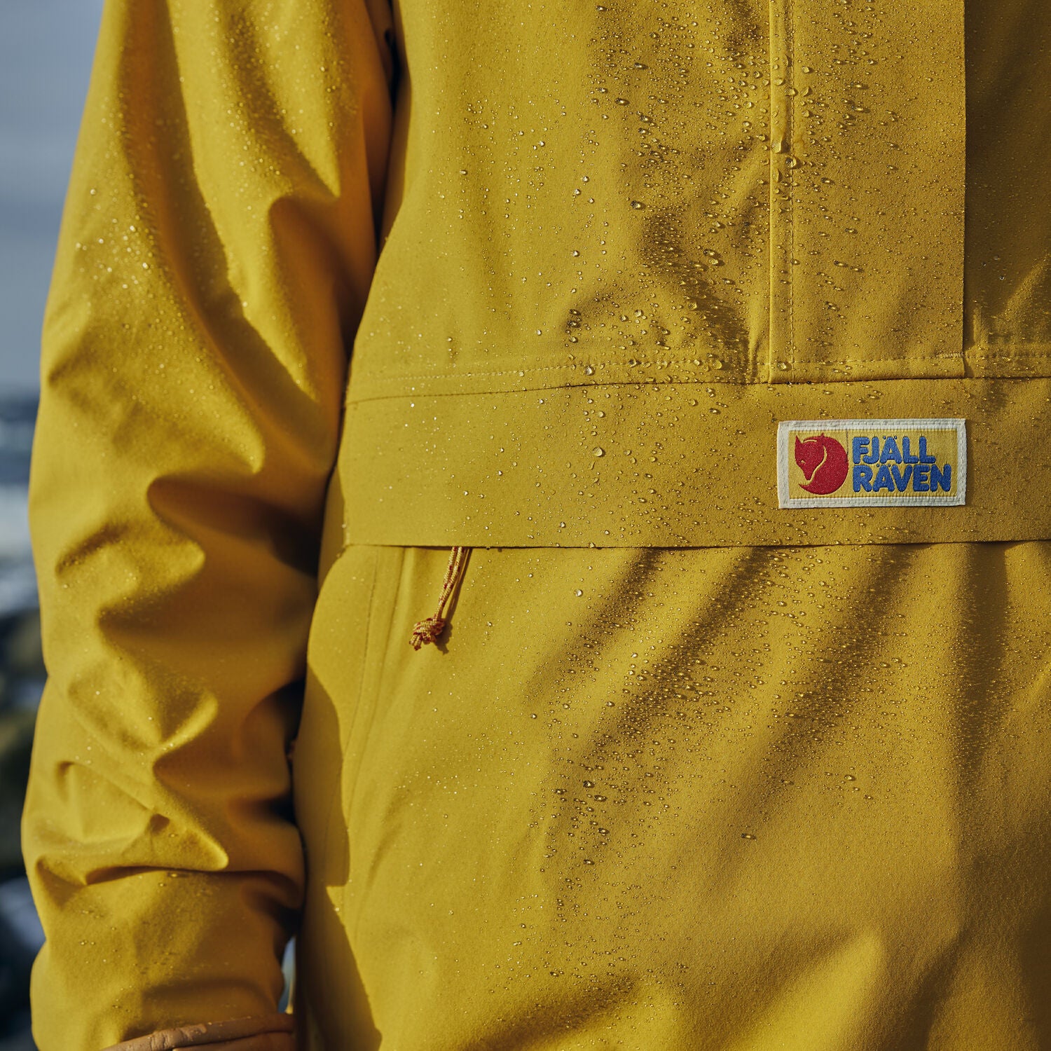 mustard yellow waterproof rain jacket with Fjällräven logo