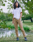 Woman standing in a park with trees and a pond in the background