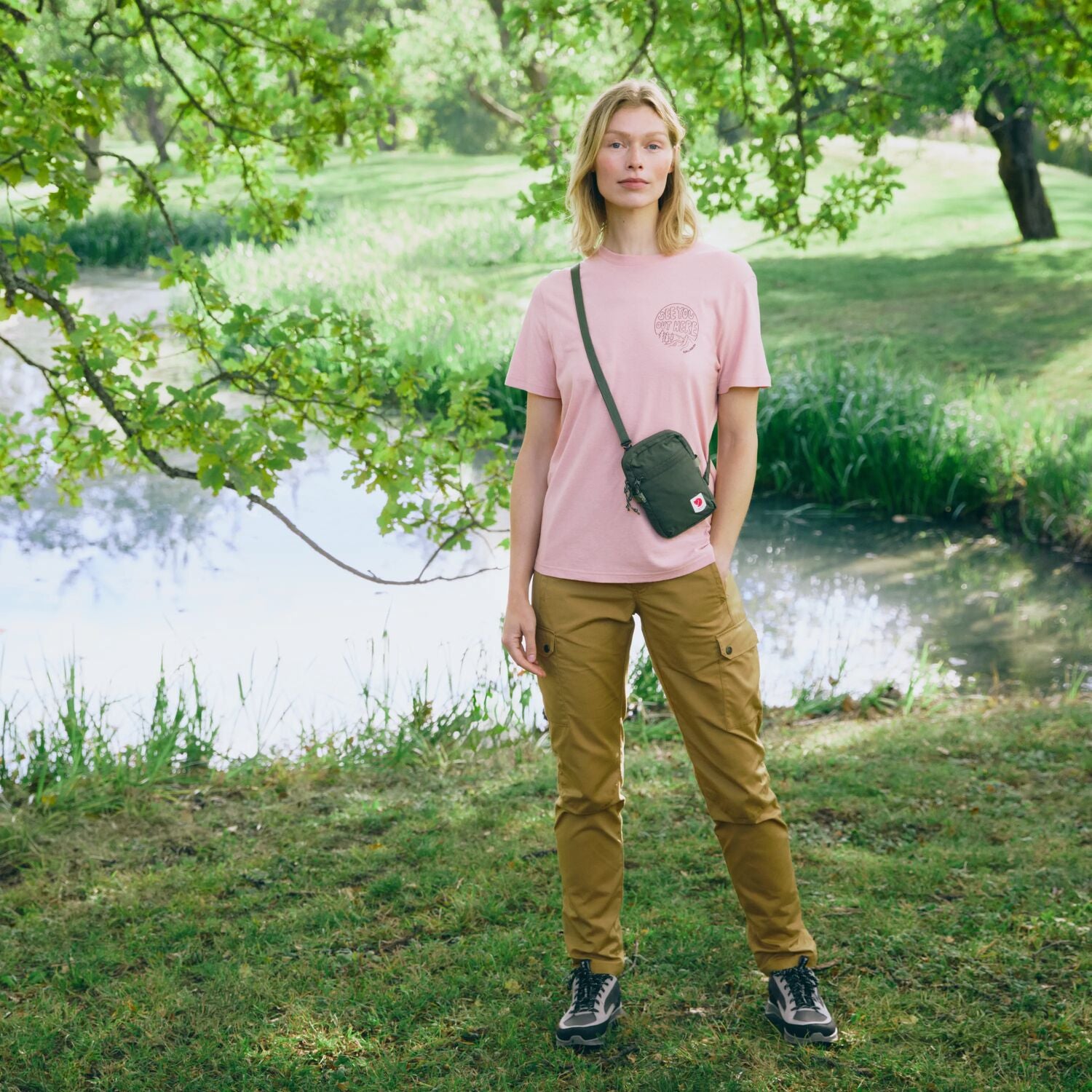 Person standing in a park with a lake and trees in the background