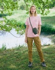 Person standing in a park with a lake and trees in the background