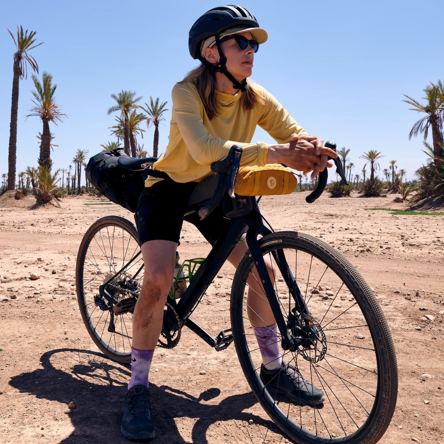 Person with a bicycle in a desert landscape with palm trees