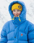 Person wearing a blue winter coat with a yellow beanie in a snowy background