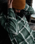 woman in patina green-deep patina  long sleeve shirt and orange beanie