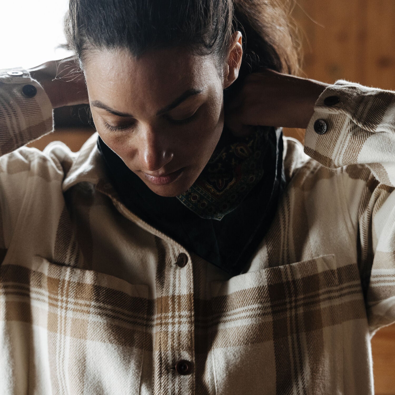 woman adjusting collar of checkered shirt