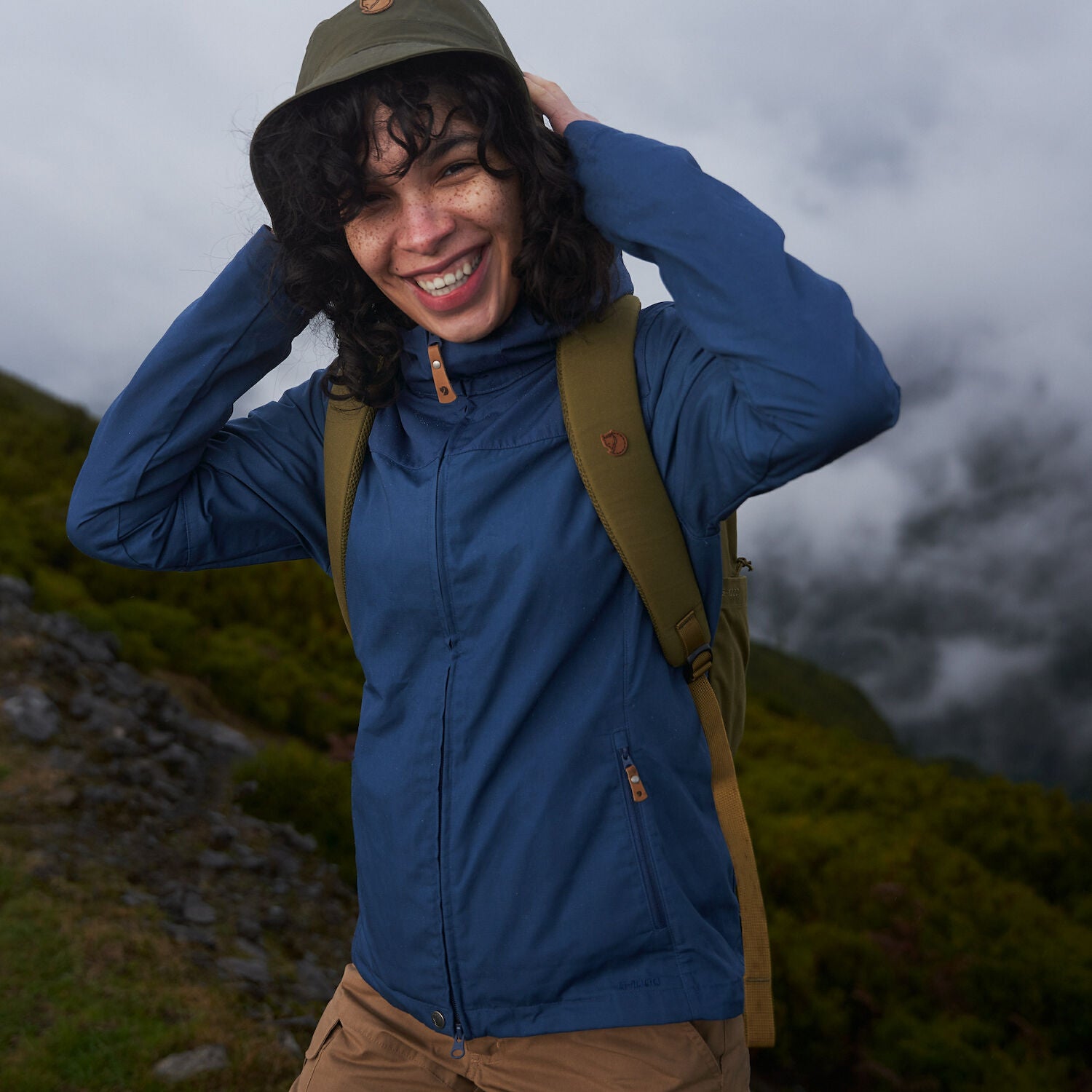 woman wearing indigo blue jacket hiking on the mountain