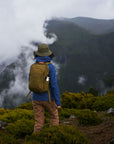 woman wearing indigo blue jacket carrying backpack hiking a mountain