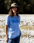 woman wearing blue round neck t-shirt and green bucket hat on rocky surface