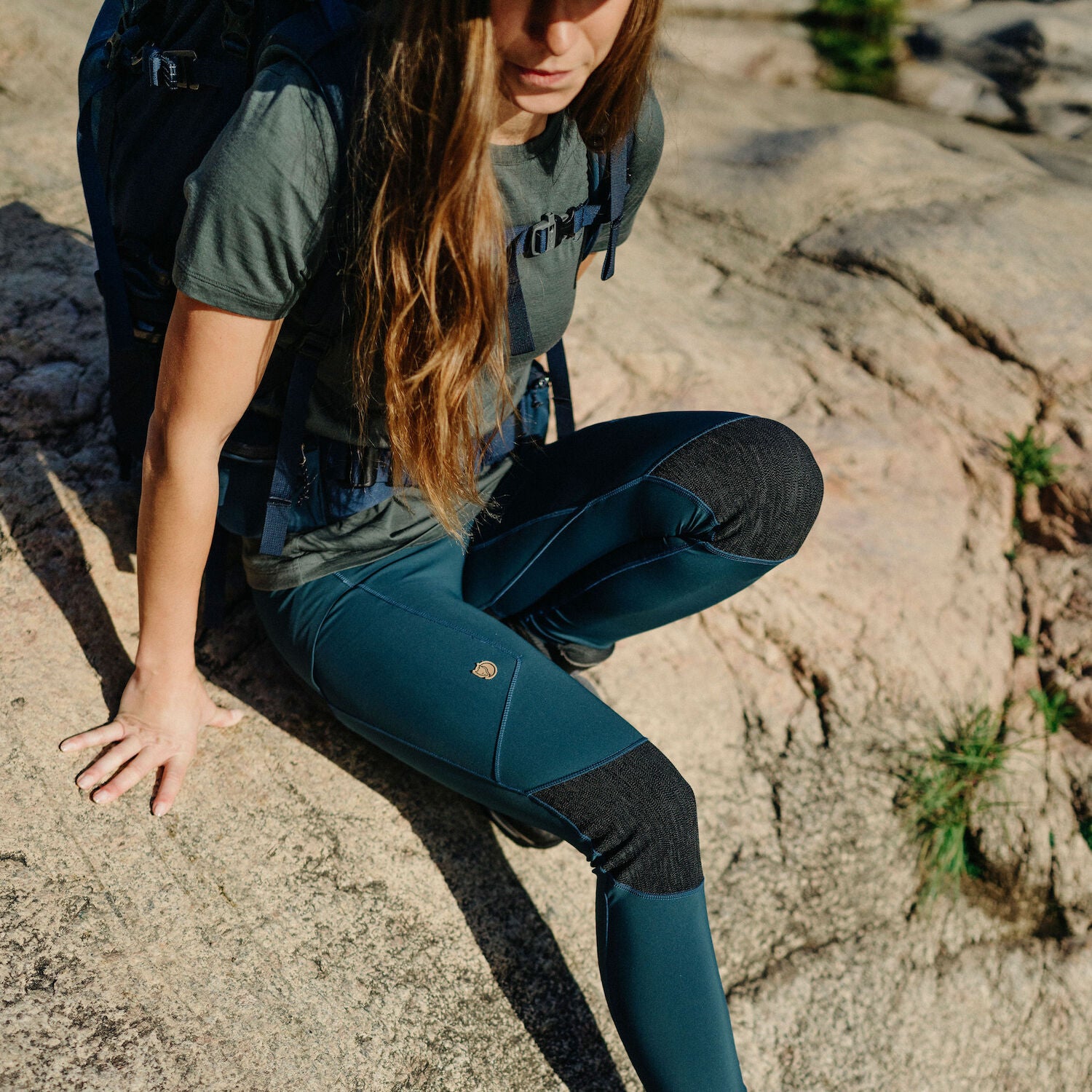 woman wearing blue tights bending down with reinforced knees and Fjällräven logo
