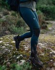 woman wearing blue tights with reinforced knees and Fjällräven logo walking on grass surface